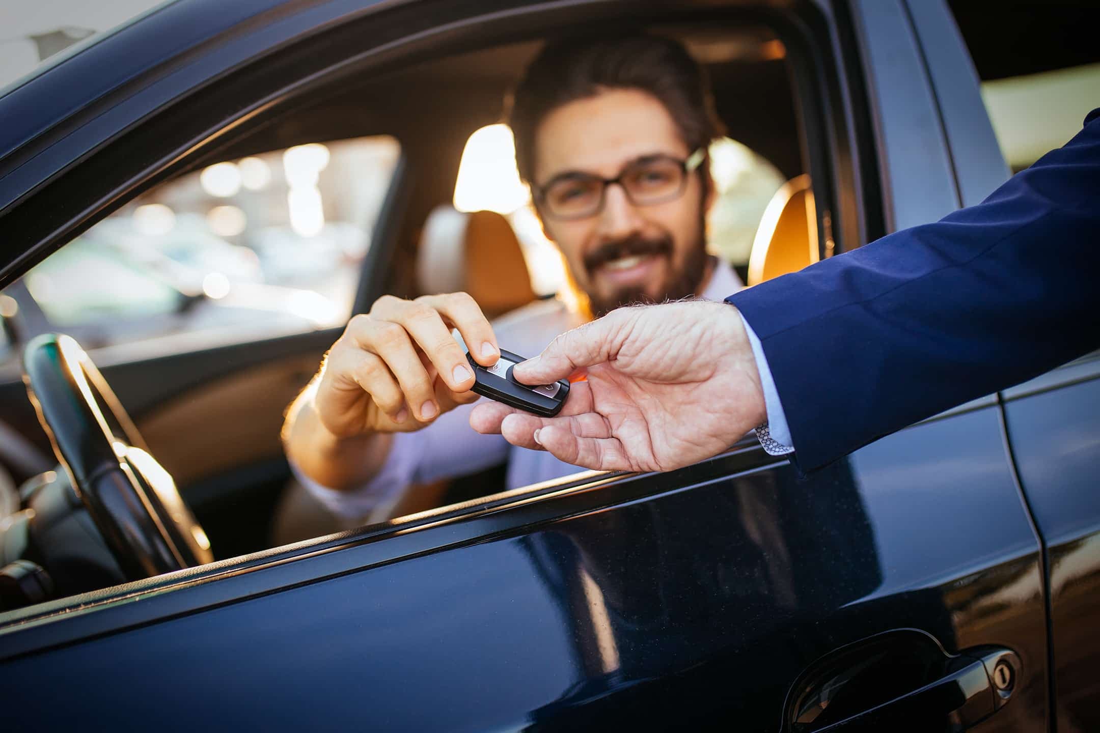 a salesman gives the keys to the car to the customer