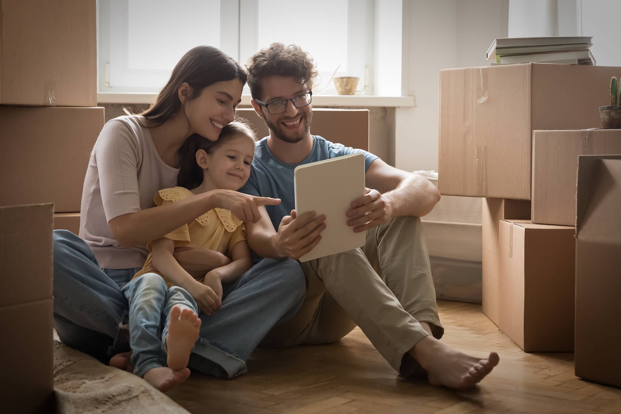 Family in a room with moving boxes looking at a screen